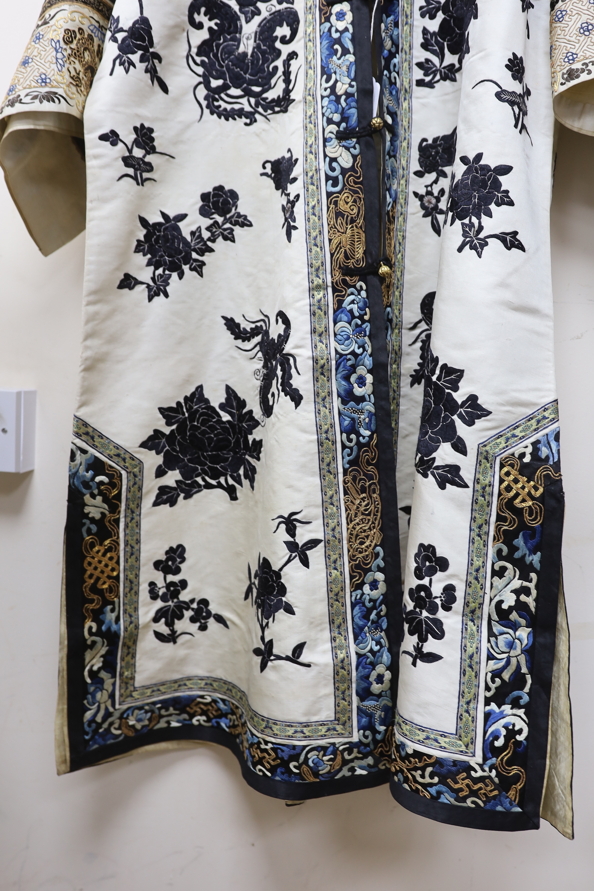 A late 19th/early 20th century Chinese embroidered cream silk robe with black symbolic embroidered all over motifs